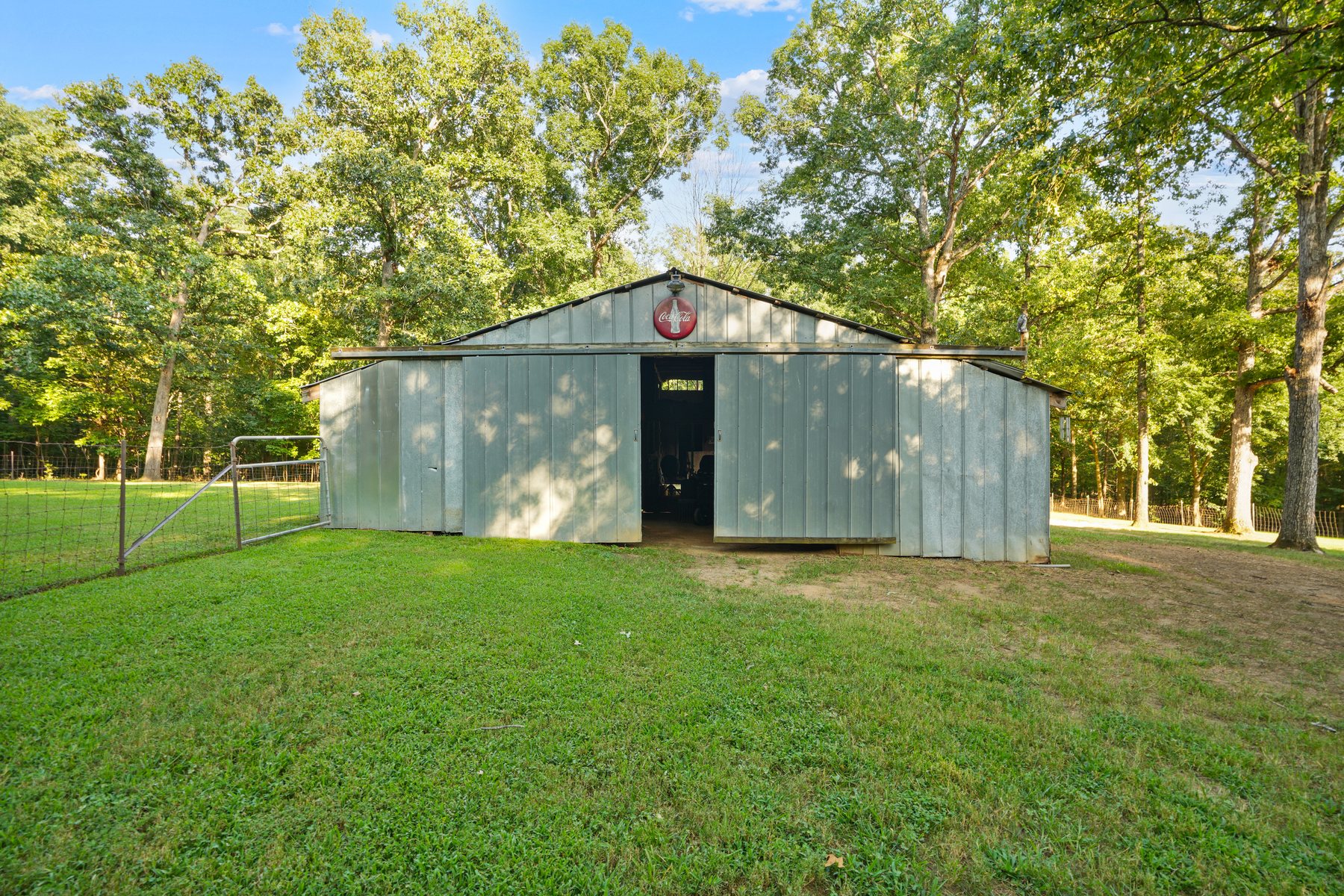 A metal barn under mature trees
