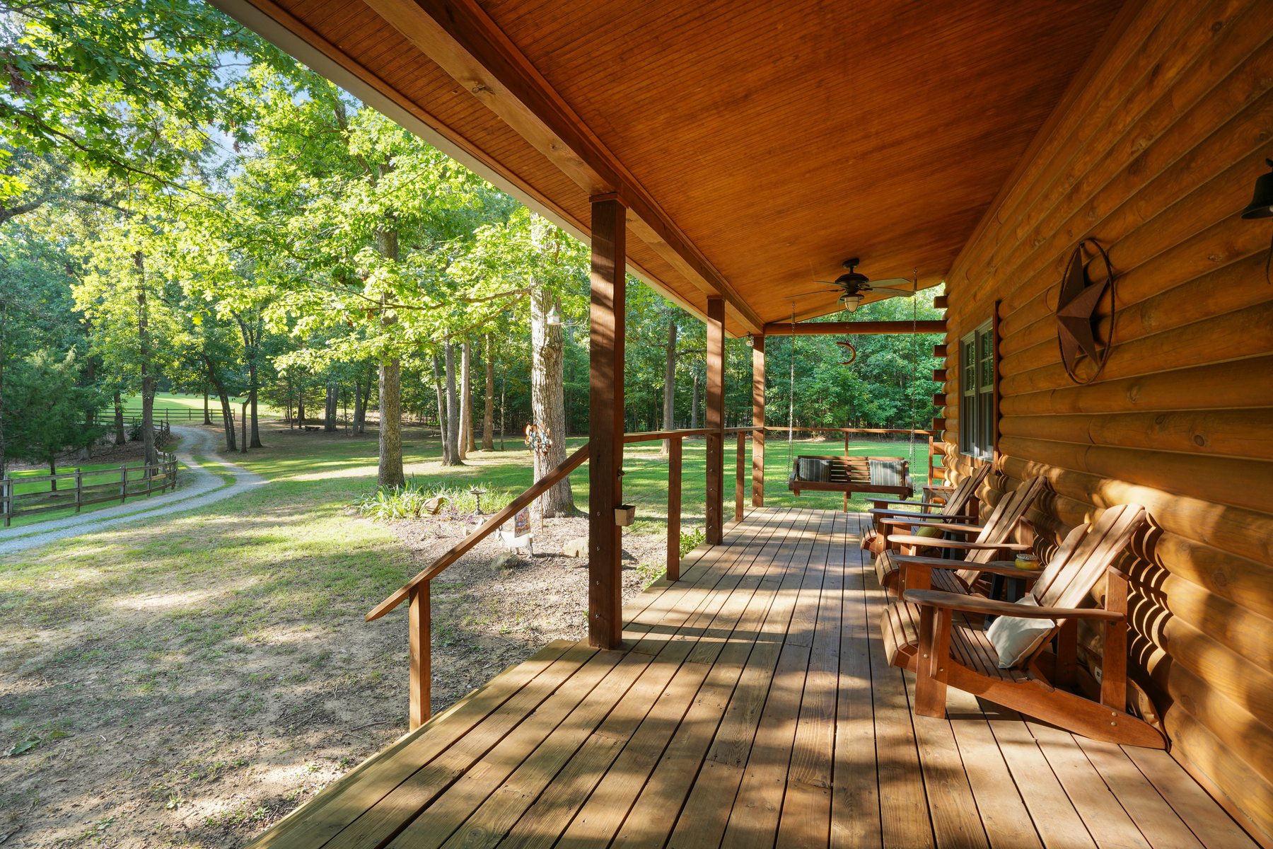 The covered porch running the length of the log house, looking out into trees
