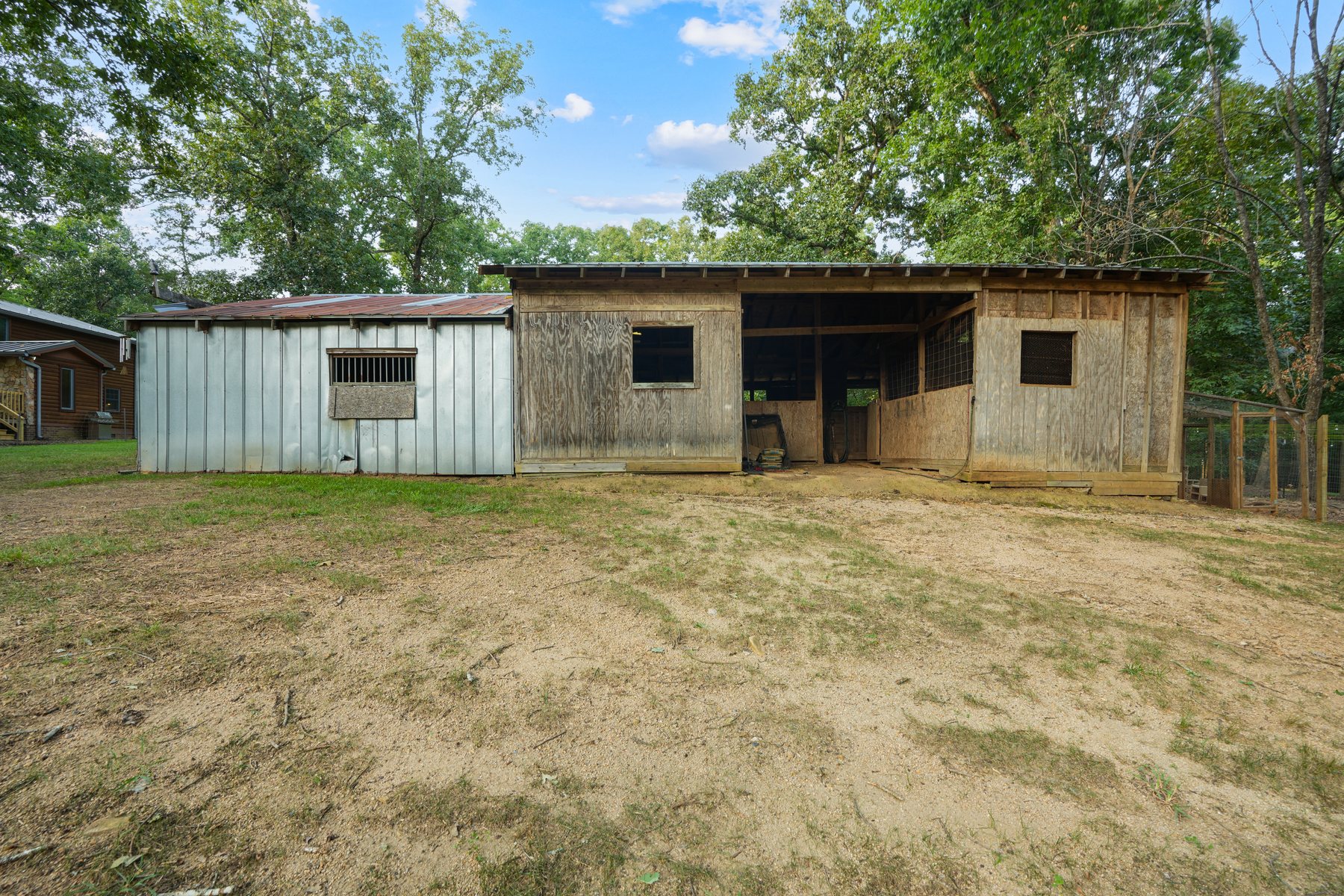 An open stable with stalls at the edge of the fenced ground